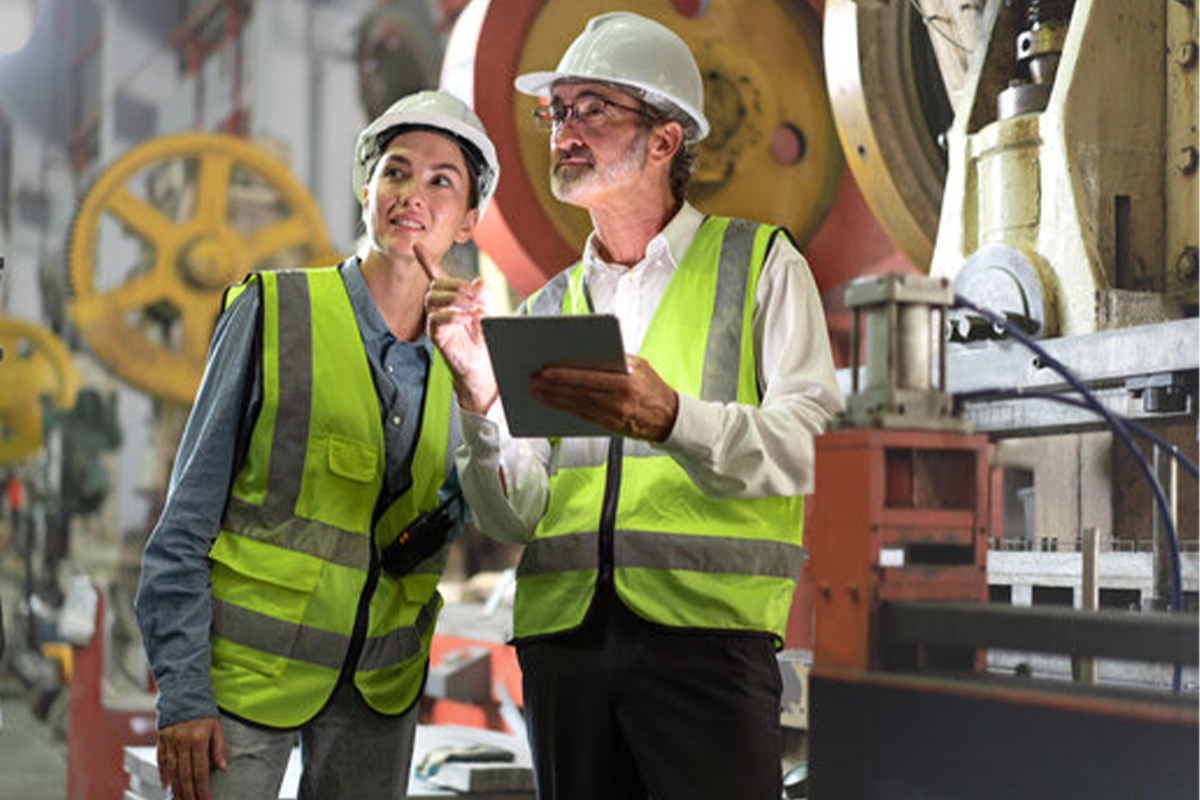 consulting-spot Senior manager train female technician to work in metalwork production factory.